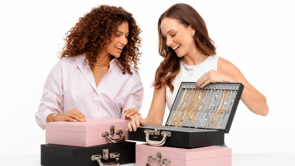 Consultora realizando a revenda de semijoias para a cliente, onde ela apresenta seu mostruário com colares, pulseiras, anéis, brincos.