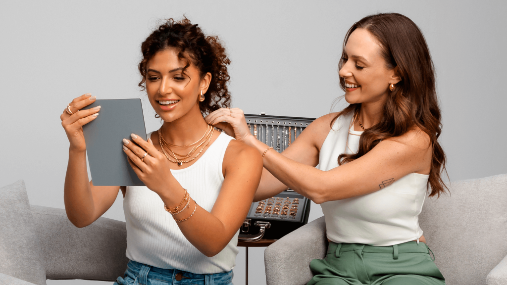 Consultora junto com a cliente apresentando o mostruário de semijoias para que ela faça a revenda das semijoias.